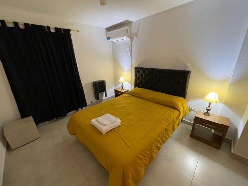 a bedroom with a yellow bed and two night stands at Departamento Macrocentro amoblado (zona Sanatorio Privado) in Río Cuarto