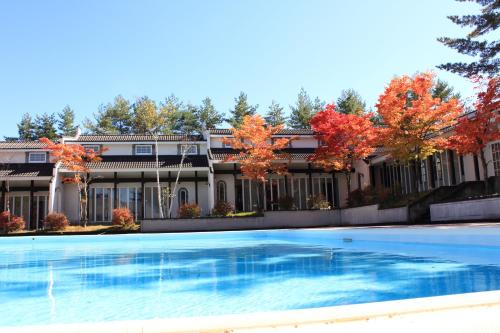een groot huis met een zwembad ervoor bij HOLIDAY VILLA Hotel & Resort KARUIZAWA in Tsumagoi