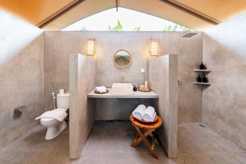 a bathroom with a sink and a toilet at Kaura Bali in Candidasa