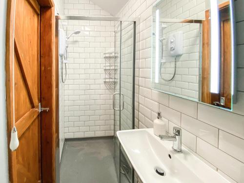 a white bathroom with a sink and a mirror at Swallows in Delabole