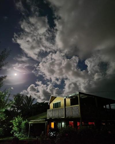 a building under a cloudy sky with the moon at Cabañas Christophe in Hanga Roa