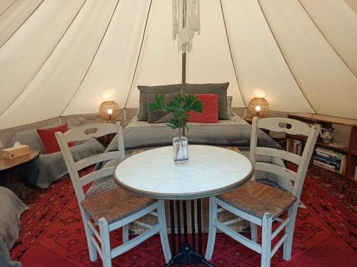 einen Tisch und Stühle in einem Zelt mit einem Bett in der Unterkunft Macedon Ranges Glamping in Macedon