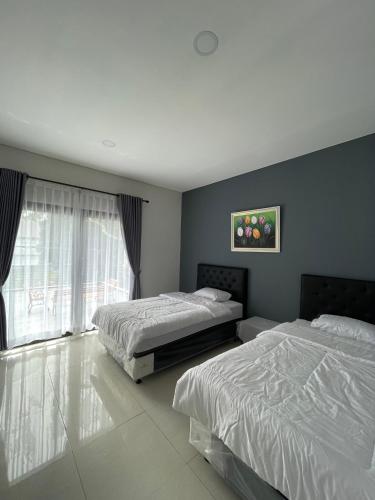 a bedroom with two beds and a window at Villa Qfa Syariah in Lembang