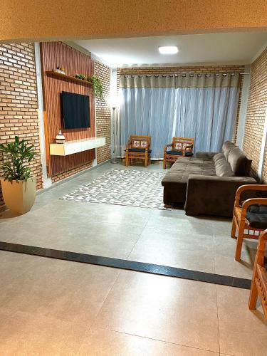 a living room with a couch and a flat screen tv at Chácara ilha do Sol com Piscina aquecida 5km do thermas in Olímpia