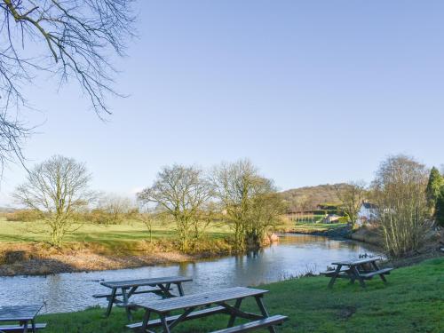 three picnic tables in a park next to a river at Briar Cottage in Great Eccleston