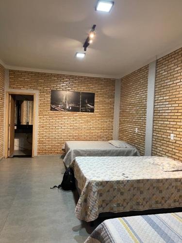 a bedroom with two beds and a brick wall at Chácara ilha do Sol com Piscina aquecida 5km do thermas in Olímpia