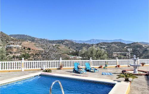 a swimming pool with chairs and a fence and mountains at Villa Pastor, Torrox, Málaga in Torrox