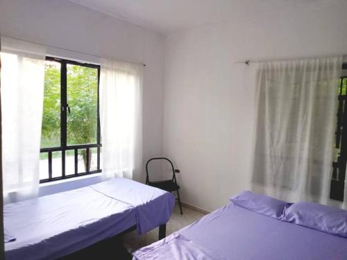 two beds in a room with a window at Apartamento vacacional piscina in Nariño