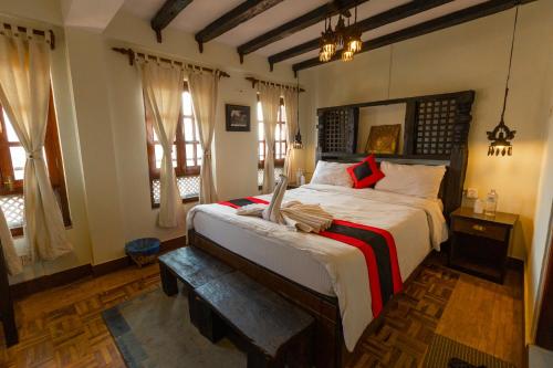 a bedroom with a large bed with a bench in it at Vajra Guest House & Restaurant in Bhaktapur