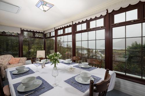 a dining room with a white table and windows at Tigh Chailein in Tarbert