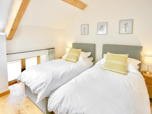 2 Betten in einem Zimmer mit weißen und grünen Kissen in der Unterkunft The Oak Stall - Uk11023 in East Worlington
