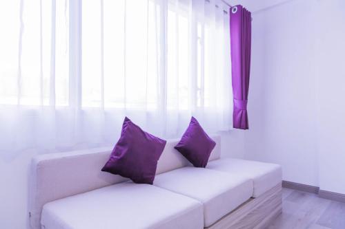 a white couch with purple pillows in a room at Hotel Zing in Pattaya South