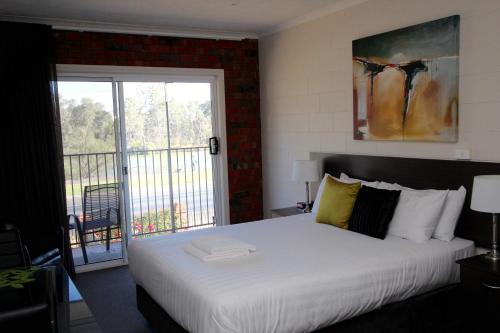 - une chambre avec un grand lit blanc et un balcon dans l'établissement Mildura Riverview Motel, à Gol Gol