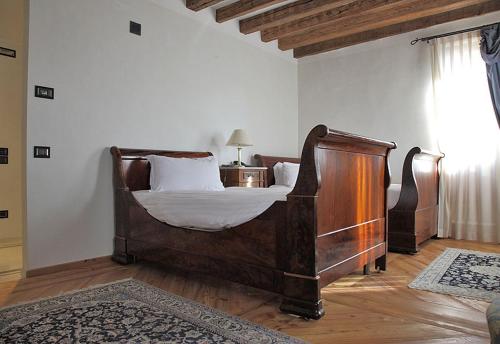 a bedroom with a wooden bed with white sheets at Park Hotel Villa Carpenada in Belluno
