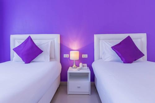 two beds in a room with purple walls at Hotel Zing in Pattaya South
