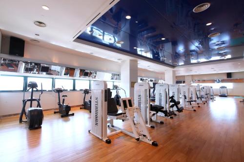 a gym with rows of treadmills and elliptical machines at Ramada Plaza by Wyndham Jeju Ocean Front in Jeju