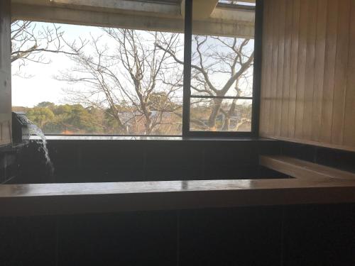 a bathroom with a large window and a bath tub at ファスティングホテル海の杜 in Kannami