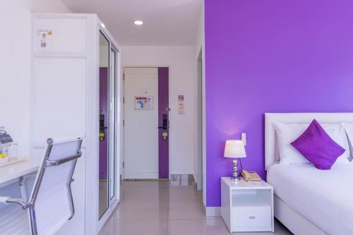 a bedroom with purple walls and a bed and a table at Hotel Zing in Pattaya South