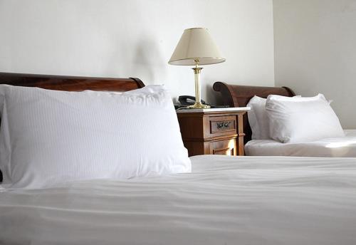 a bed with white sheets and a table with a lamp at Park Hotel Villa Carpenada in Belluno