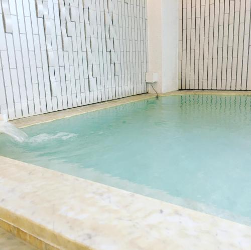 a swimming pool with blue water in a building at ファスティングホテル海の杜 in Kannami