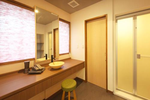 a bathroom with a sink and a mirror and a stool at Meitei no Yado Hotel Koshien in Fuefuki