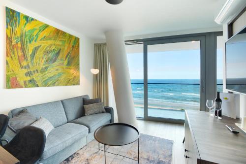 een woonkamer met een bank en uitzicht op de oceaan bij Luksusowe Apartamenty Sea Towers SeaView by Rent like home in Międzyzdroje