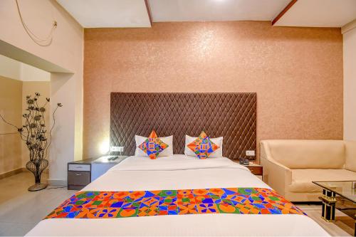 een slaapkamer met een groot bed en een stoel bij FabHotel Prime Rockstar Suites in Calcutta