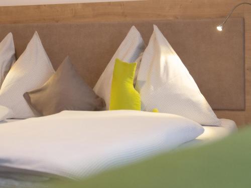 a bed with white sheets and yellow pillows at Haus Rainer in Mühlbach am Hochkönig