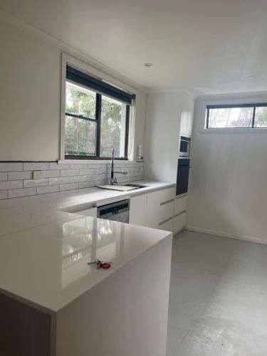 cocina blanca con fregadero y 2 ventanas en Glenaire Apartments at Frazer St, en Strahan