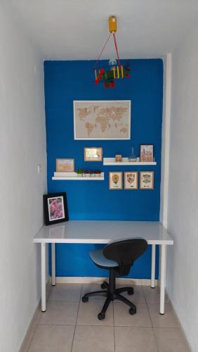 a desk with a chair and a blue wall at Dora's House comfortable apartment with a yard and view in Pyrgadikia
