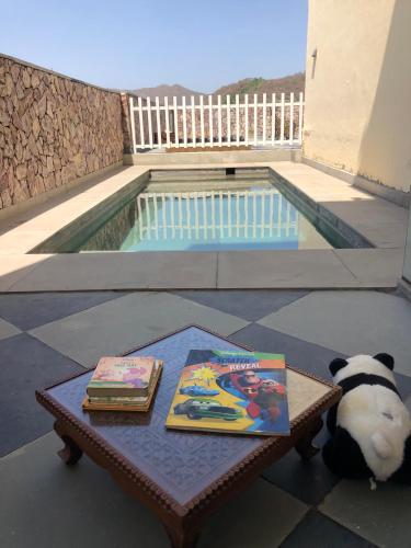 a panda bear sitting on a table with two books at Jai Villa Homestay in Udaipur