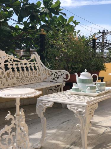 a white bench and a table with a tea set on it at Jai Villa Homestay in Udaipur