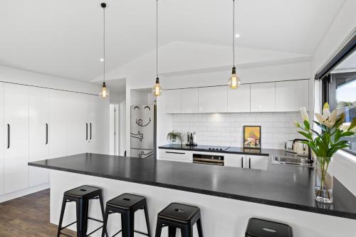 a kitchen with white cabinets and black counter stools at Wanderlust - Queenstown Holiday Home in Queenstown