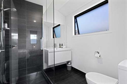 a bathroom with a shower and a toilet and a sink at Wanderlust - Queenstown Holiday Home in Queenstown