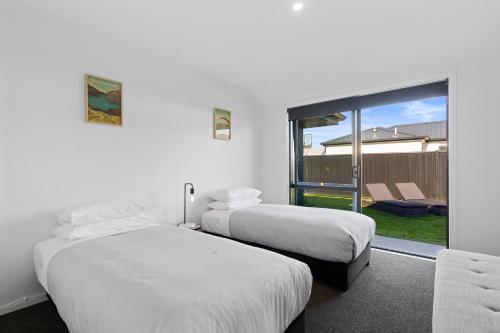 a hotel room with two beds and a balcony at Wanderlust - Queenstown Holiday Home in Queenstown