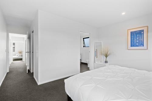 a white bedroom with a large white bed in it at Wanderlust - Queenstown Holiday Home in Queenstown