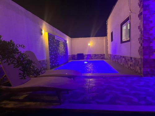 Naj‘ al AḩwālにあるNubian Villa with Private Poolの紫色の照明が付いた客室内のスイミングプール