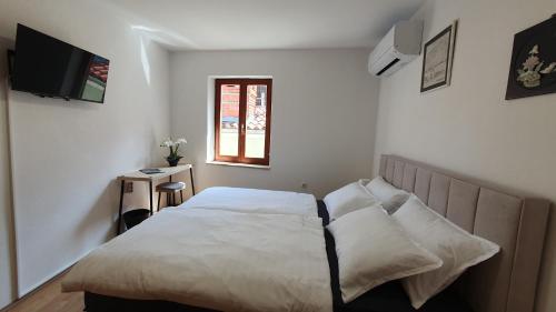 a bedroom with a bed with white sheets and a window at Holiday House Erna in Izola