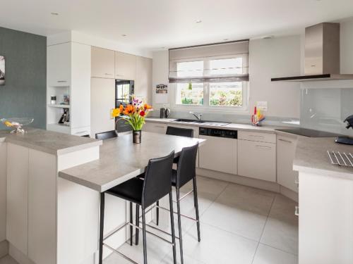 une cuisine avec des armoires blanches et une table avec des chaises dans l'établissement L escale bretonne- séjour chez l habitant, à Mordelles