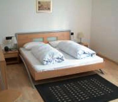 a bed with a wooden headboard and a black rug at Pension Angergut in Cermes