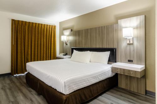 una habitación de hotel con una cama grande con sábanas blancas en Rodeway Inn Enumclaw Mount Rainer-Crystal Mountain Area, en Enumclaw