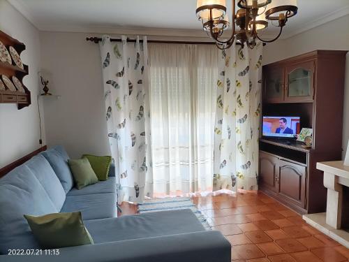 a living room with a blue couch in front of a window at Apartamento Praia da Torreira in Torreira