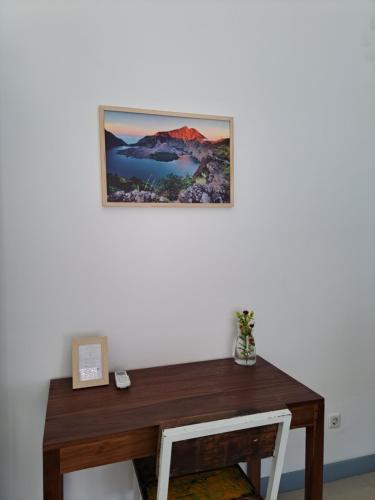 a picture hanging on a wall above a wooden desk at Kubuwatu Boutique Accommodation in Gili Trawangan