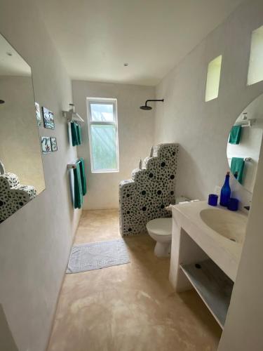 a bathroom with a sink and a toilet and a mirror at The Shore House Diani - 2 Bedroom Villa with a pool in Galu