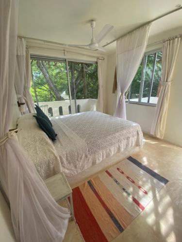 a bedroom with a bed with curtains and a rug at The Shore House Diani - 2 Bedroom Villa with a pool in Galu