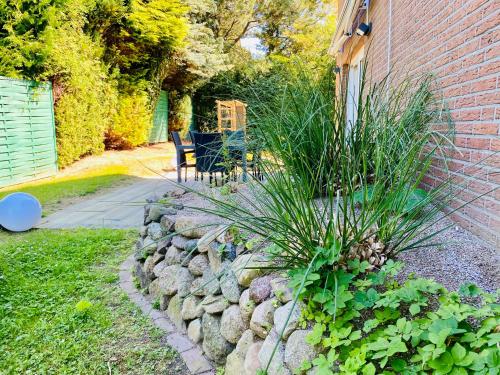 a garden with a rock wall next to a house at FeWo MEERESBRISE - Familie- Hunde - Strandnah - Garten-Seeblick - Sauna & Wellness in Sierksdorf
