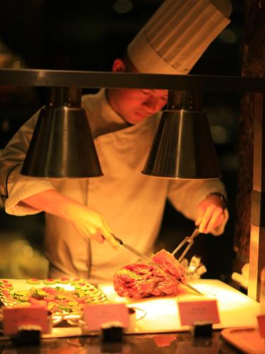 a person cooking food in a kitchen with tongs at Zhuhai Charming Holiday Hotel-Free Welcome Fruit Plate in Zhuhai