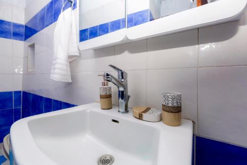 a white sink in a bathroom with blue and white tiles at Vitos Village House in Ágios Matthaíos
