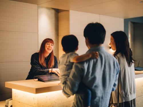 a woman standing in front of a desk with three children at MIMARU OSAKA SHINSAIBASHI EAST in Osaka