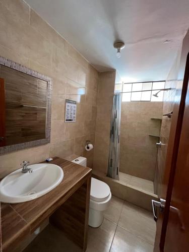 een badkamer met een wastafel, een toilet en een douche bij Antara Hostal in Cajamarca
